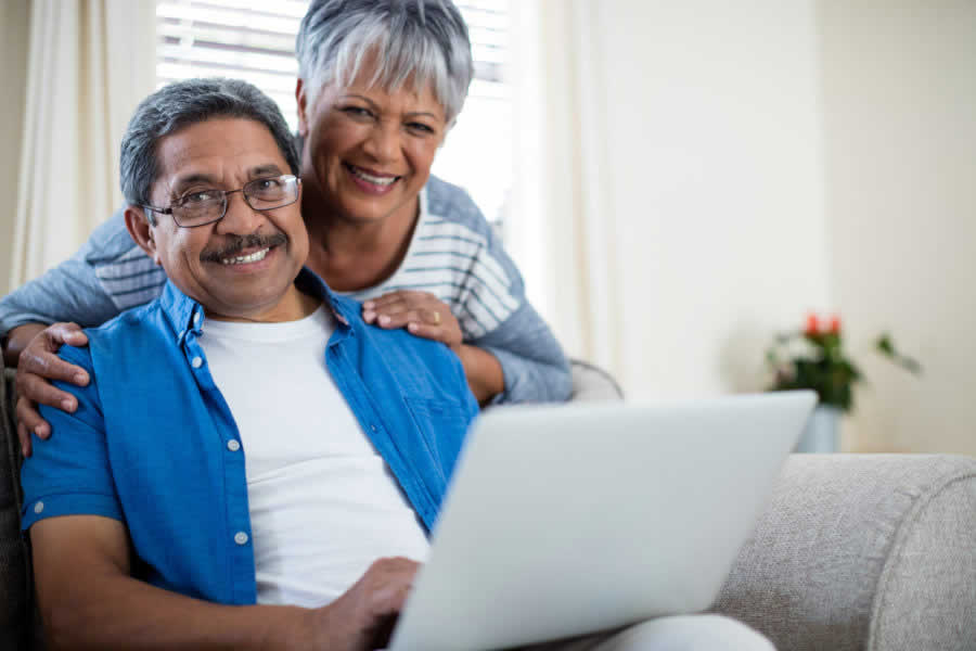 Senior couple using laptop in living room at home