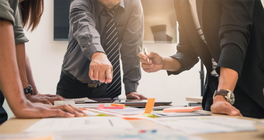 homem aponta para mesa com papeis e post its - prevenir crise de imagem