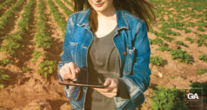 mulher segurando um tablet no campo - comunicação no agronegócio