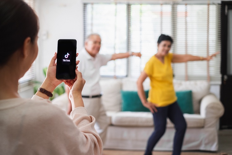 Dois senhores fazendo uma coreografia, enquanto jovem filma para o tiktok